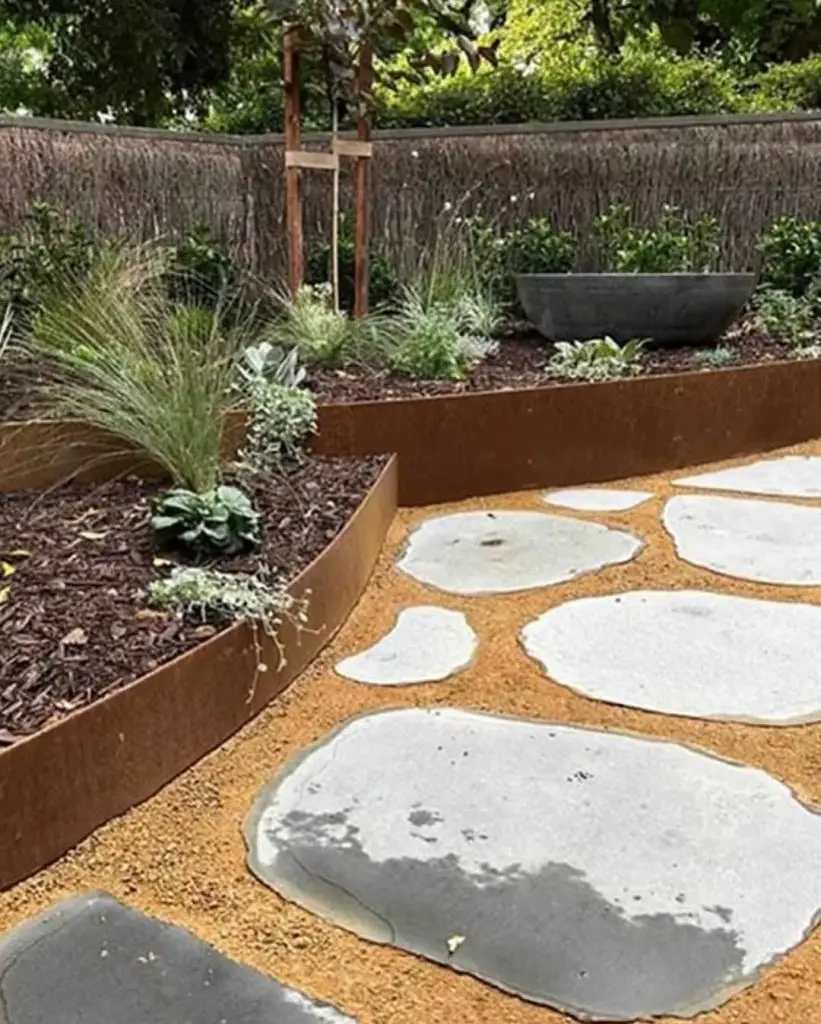 Curved steel planters with stepping stones and desert plants