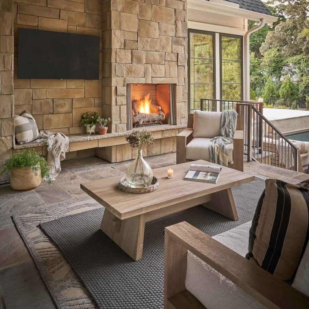 Outdoor living space with stone fireplace and wooden furniture