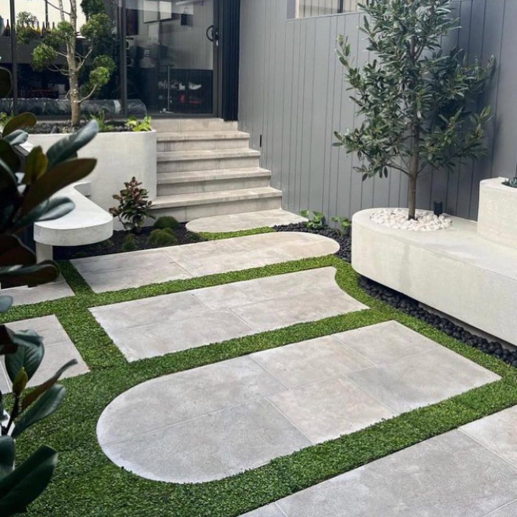 Gray stone path leading to curved bench under large ferns