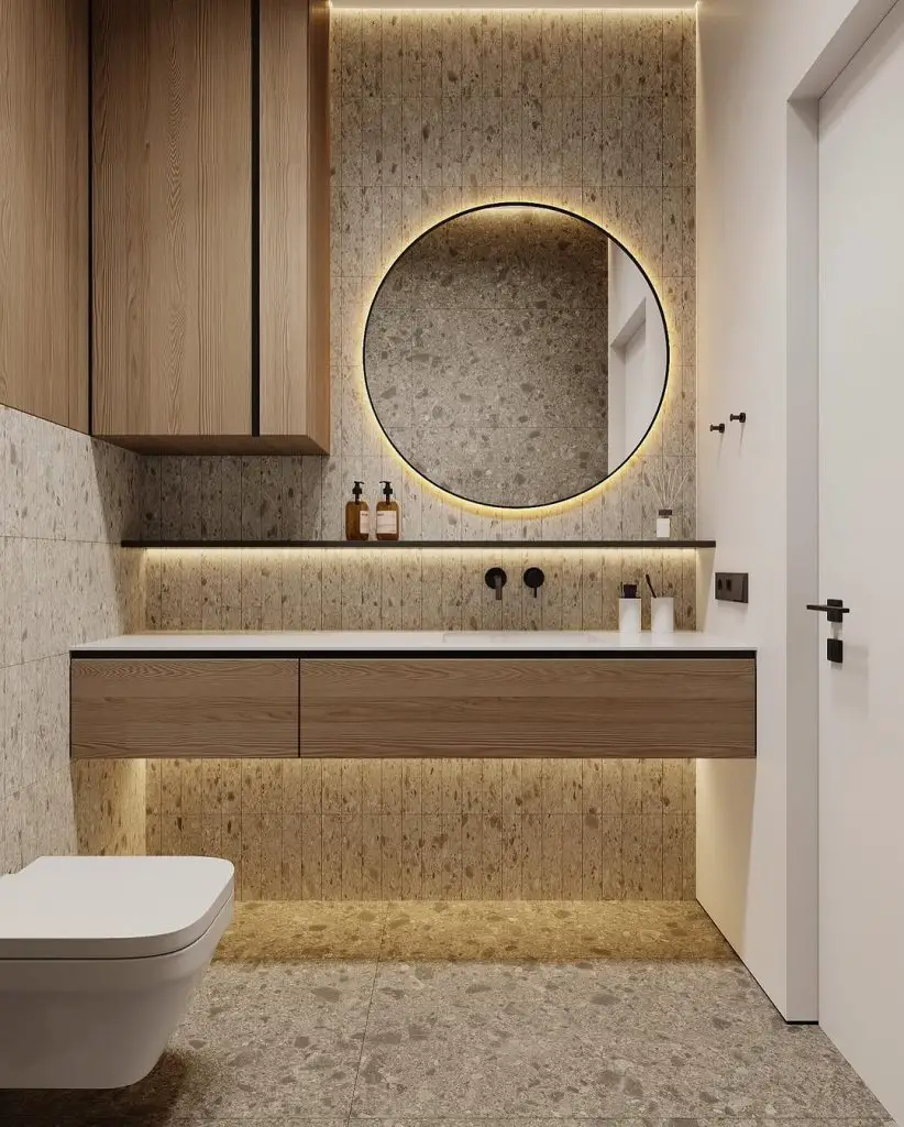 Modern bathroom with terrazzo walls backlit round mirror and wooden floating vanity