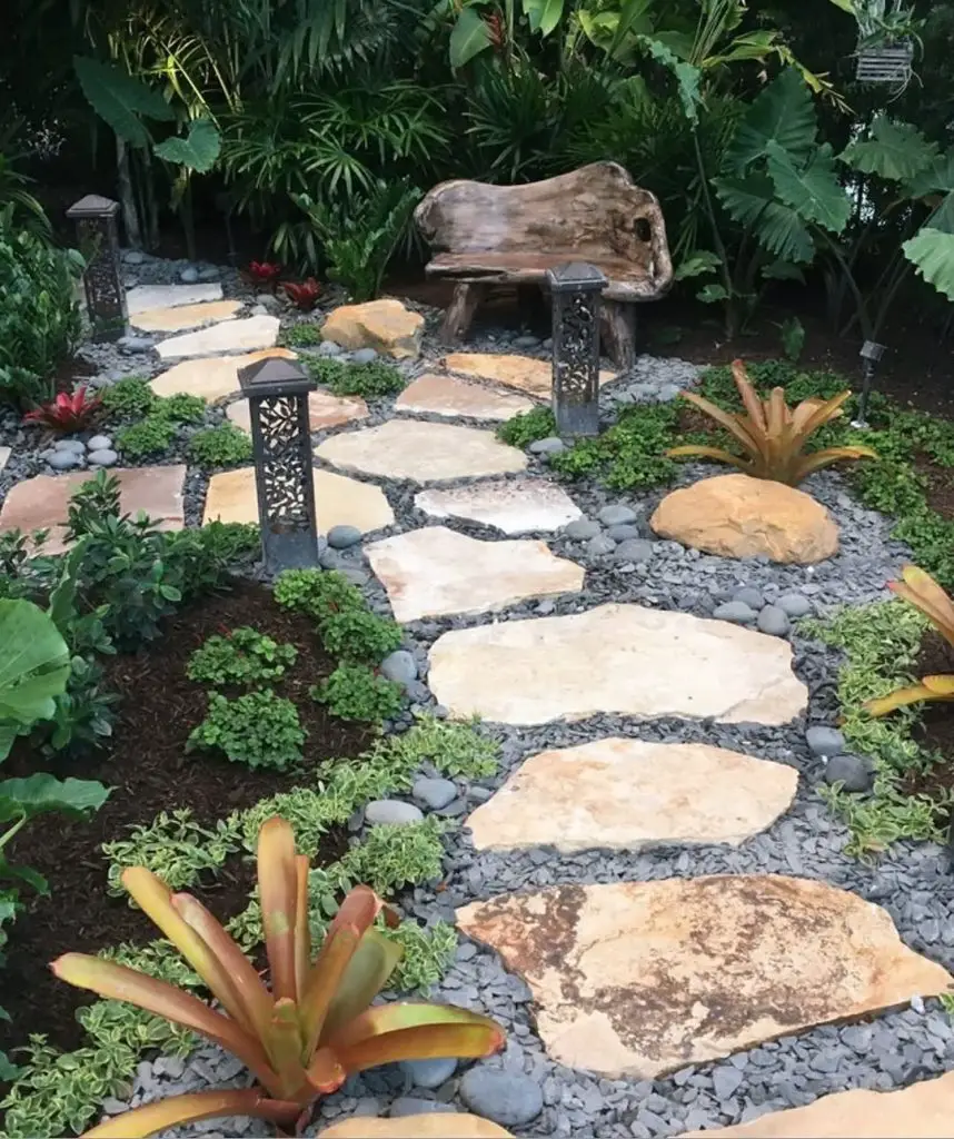 Black stepping stones leading to turquoise door through bamboo garden