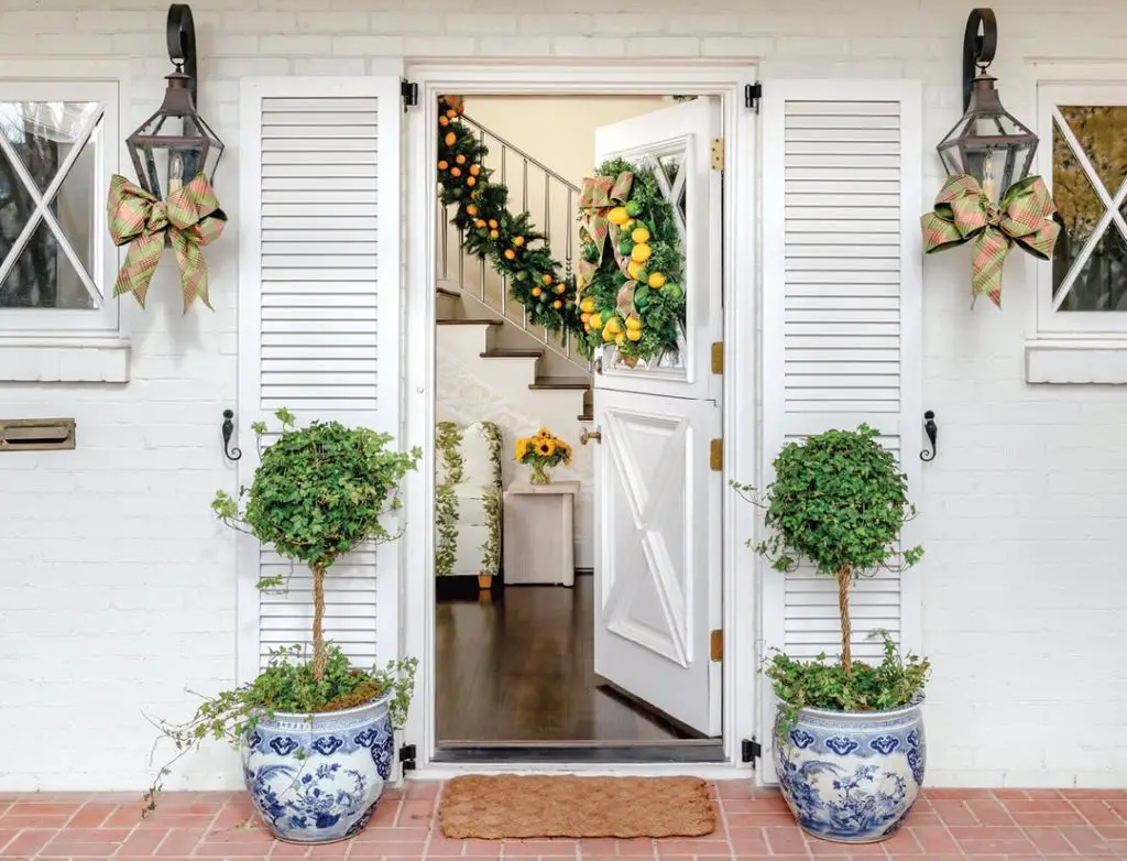 White colonial entrance with topiaries and citrus garland