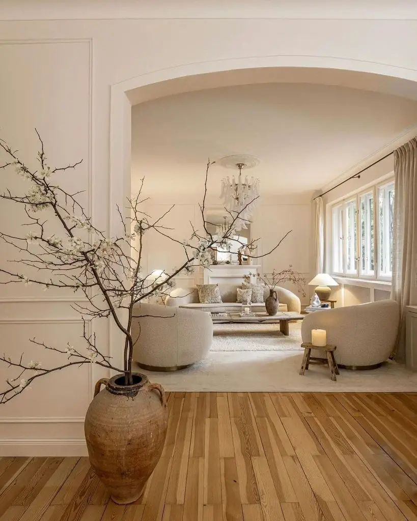 White living room with flowering branches and curved seating