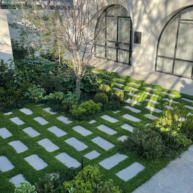 Geometric concrete pavers arranged in grass with modern building backdrop
