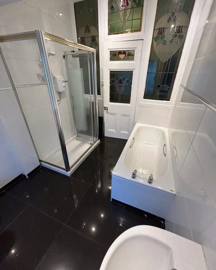 White bathroom with stained glass door shower enclosure and bathtub