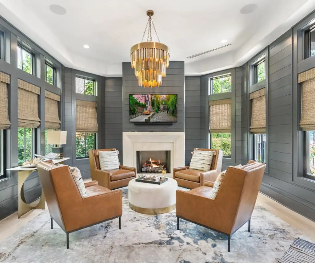 Modern sunroom with gray walls leather chairs and gold chandelier