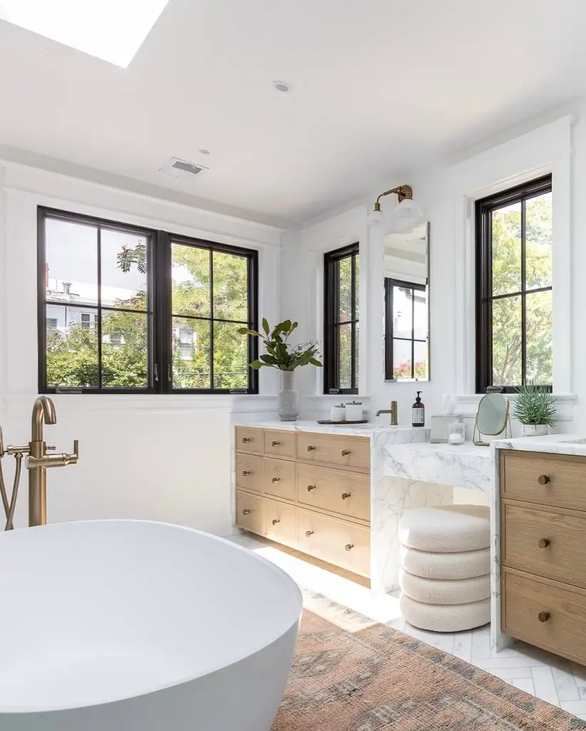 Modern bathroom with freestanding tub natural wood vanity and black framed windows