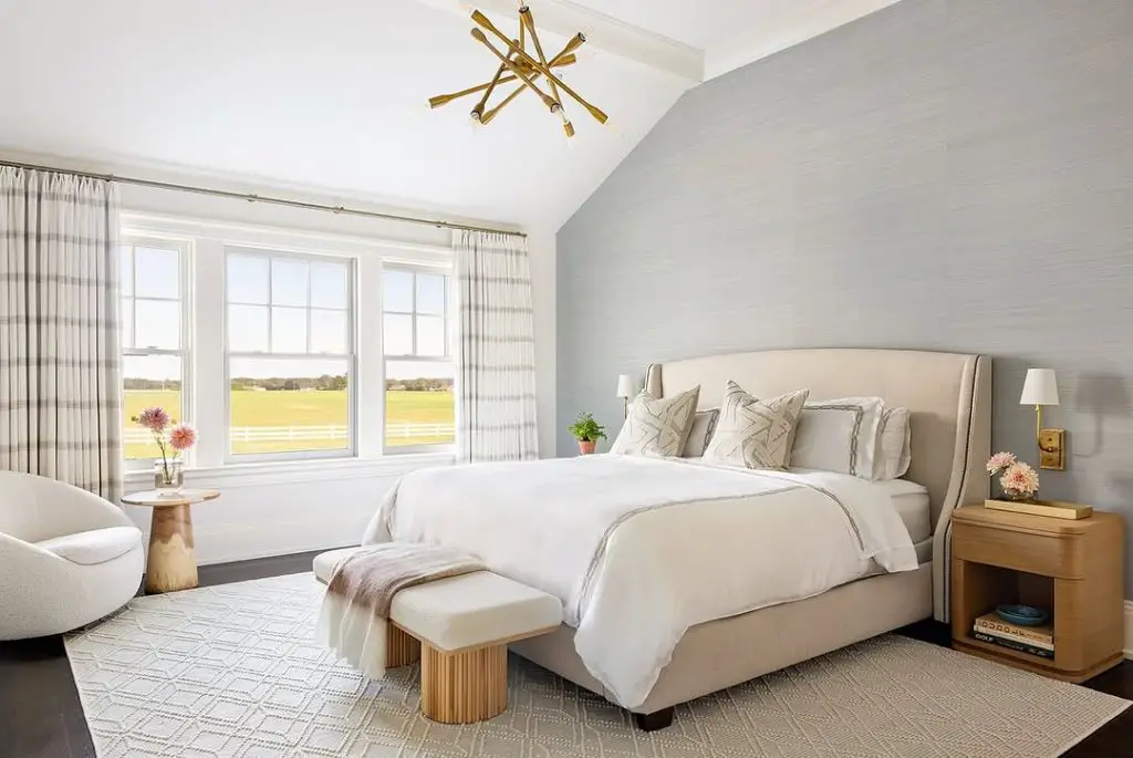 Bright modern bedroom with brass chandelier and countryside views