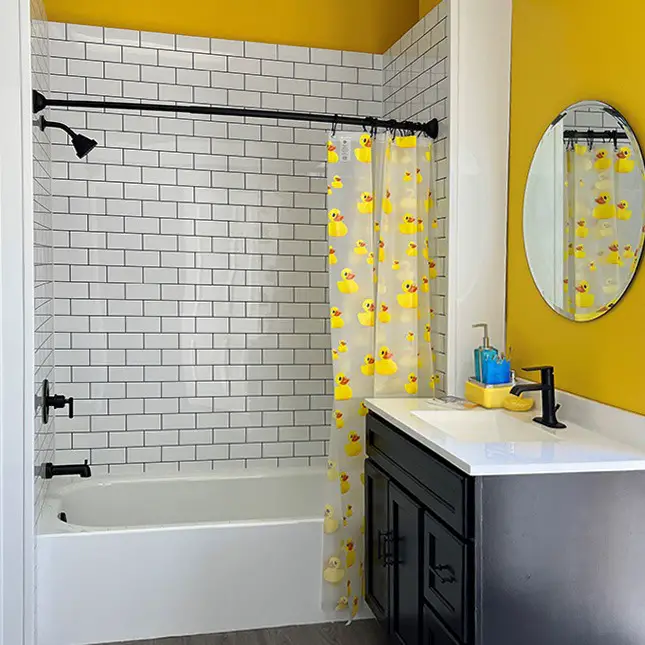 Yellow bathroom with rubber duck shower curtain and black fixtures