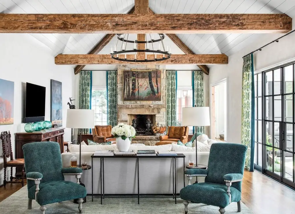 Living room with wooden beams stone fireplace and teal chairs