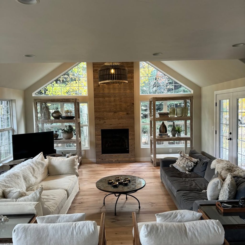 Bright living room with vaulted ceiling wooden fireplace and glass shelving