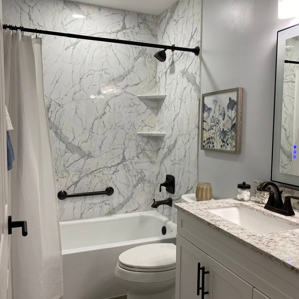 Bathroom with marble walls floating shelves and black fixtures
