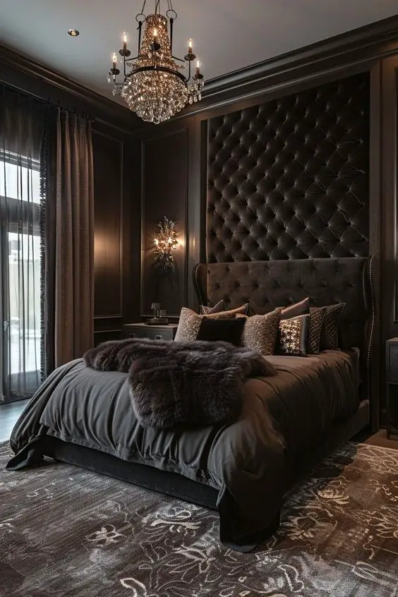Dark bedroom with tall tufted headboard crystal chandelier and fur throws