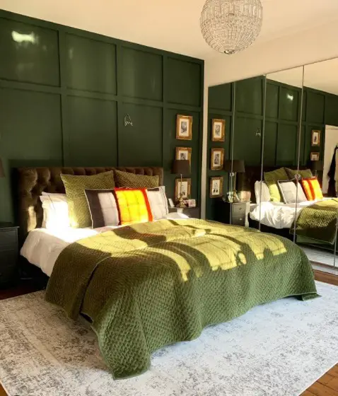 Dark green bedroom with wooden ceiling beams rattan lights and quilted bedding