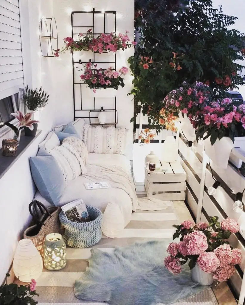 White cushioned seating area with pink flowers and decorative lanterns on balcony