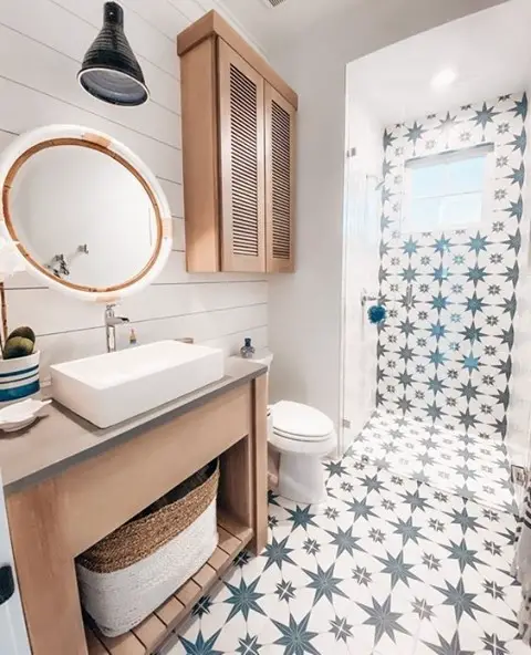 Modern bathroom with blue star patterned tiles and copper round mirror