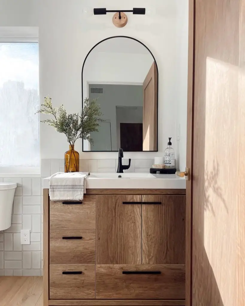 Modern bathroom with wooden vanity white sink amber vase and black fixtures
