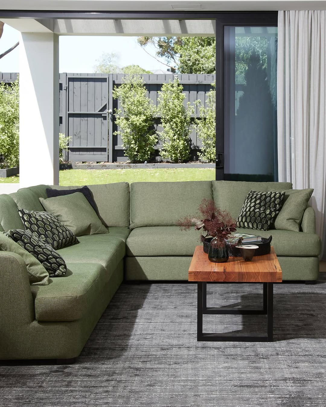 Modern green and gray living room with brass lighting and plants