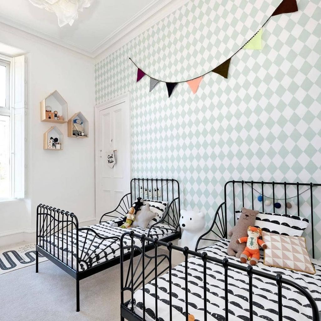 Shared kids bedroom with twin black metal beds mint geometric wallpaper and house shelves