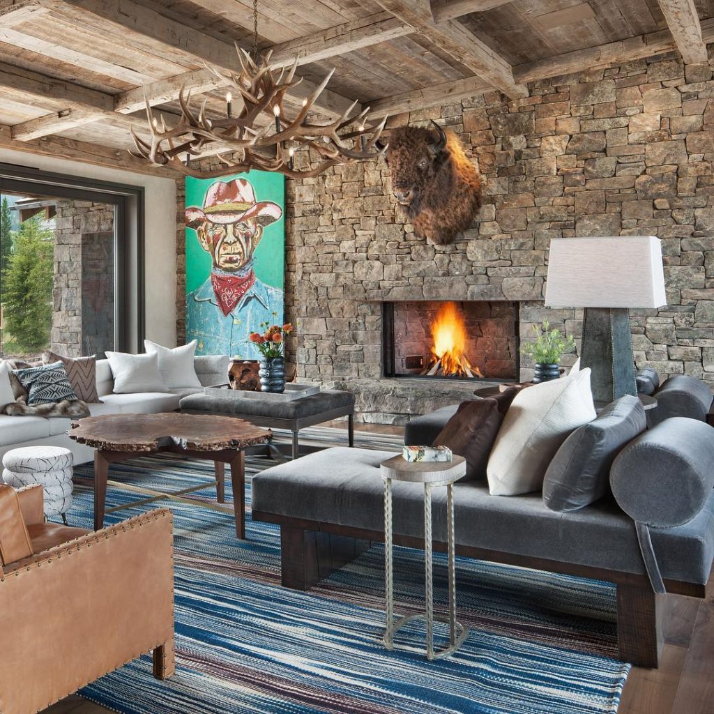 Modern rustic living room with antler chandelier stone fireplace and western art