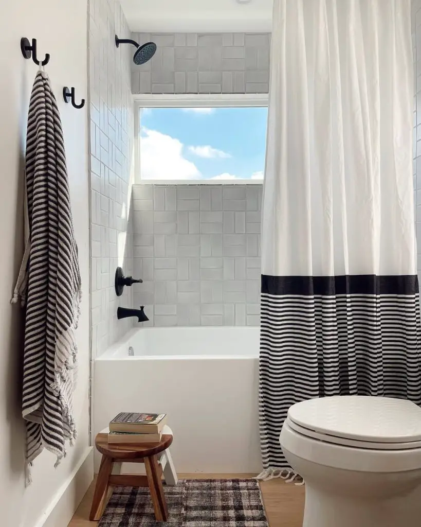 White bathroom with striped curtain wooden stool and black accents