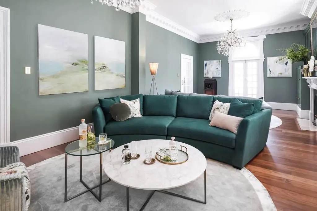 Living room with sage walls teal sectional and crystal chandeliers