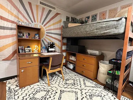 Minimalist dorm room with bunk bed black futon and geometric rug