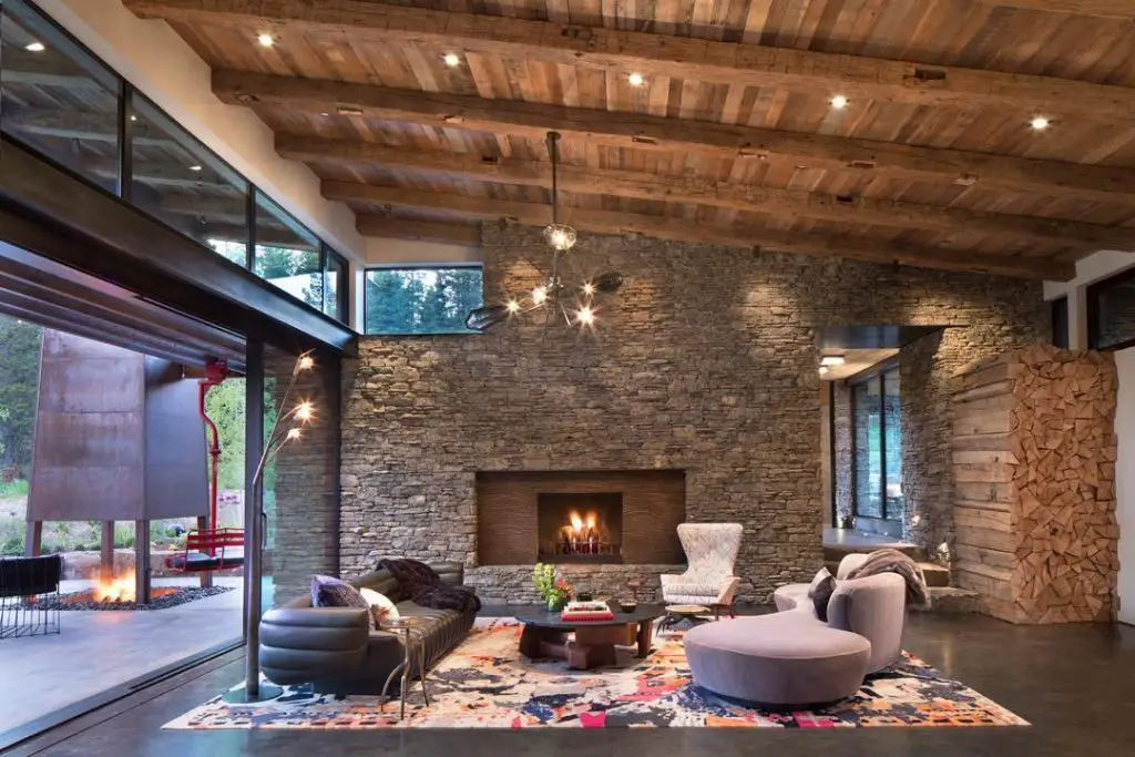 Modern mountain home living room with panoramic windows and stone fireplace