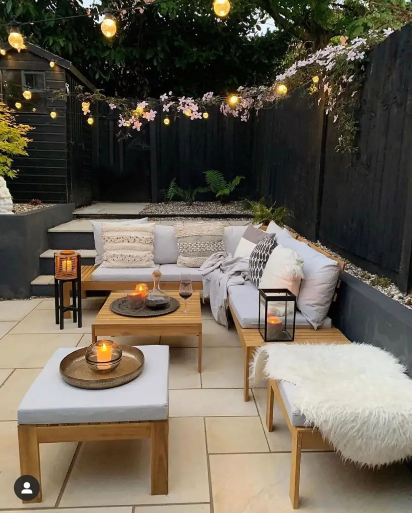 Outdoor patio with string lights wooden furniture and white cushions
