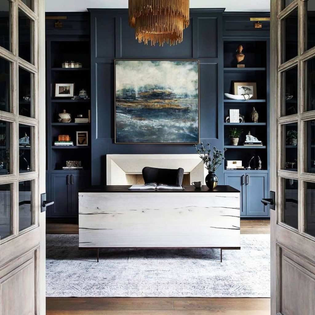 Modern dual desk setup with grey shelving unit and geometric art