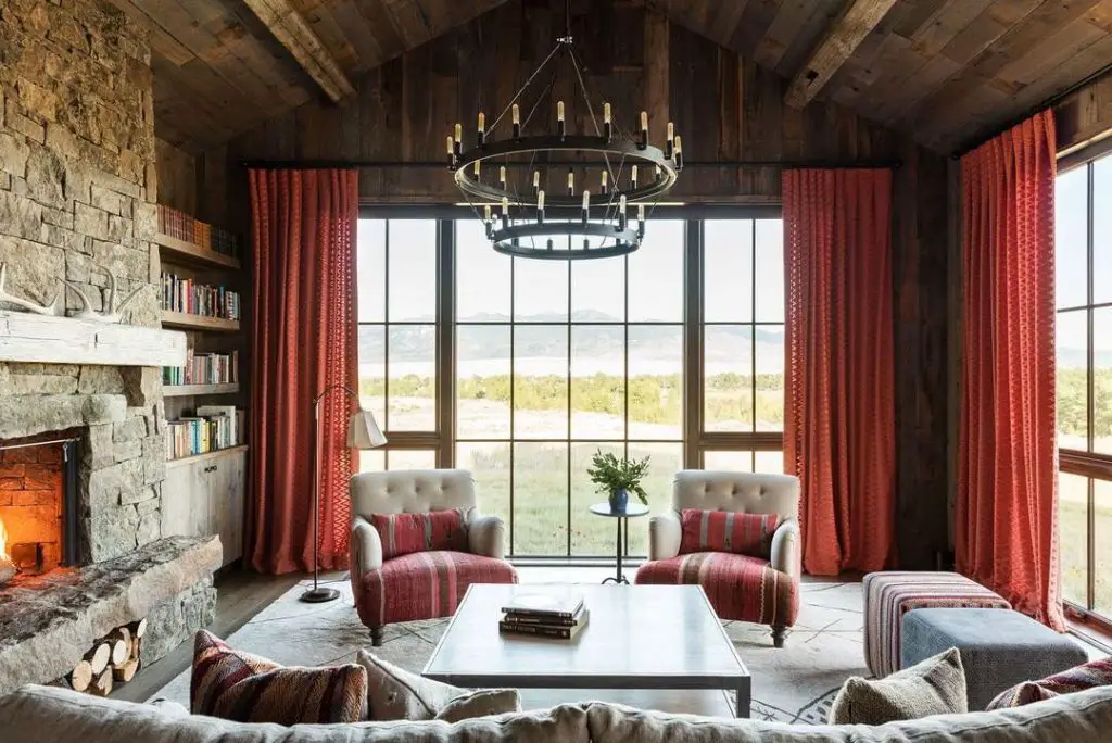 Rustic library room with stone fireplace built in bookshelves and comfortable seating