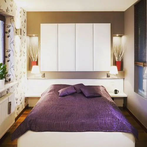Small bedroom with built in storage purple bedding and wall mounted lights