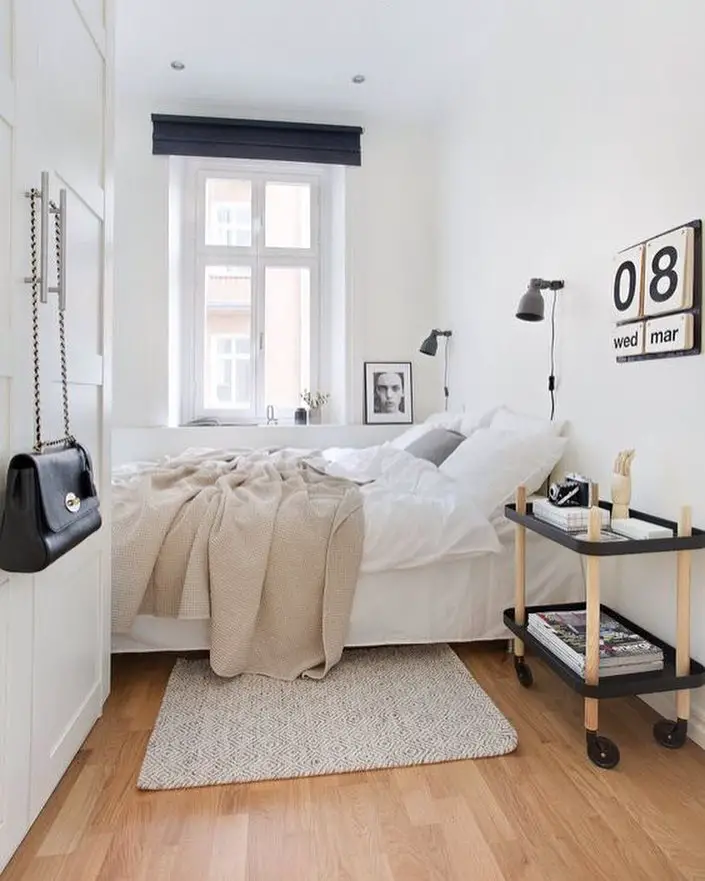 Minimalist bedroom with white bedding black accents and portable side table