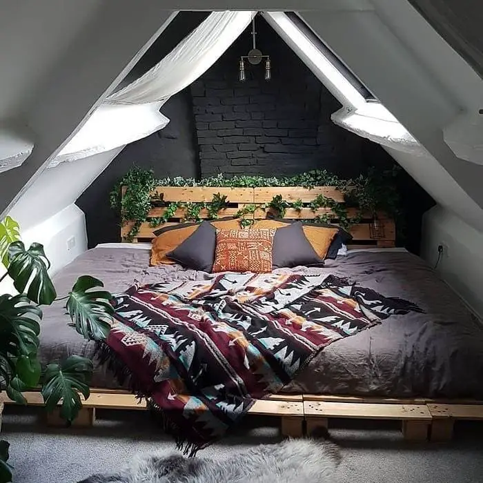 Attic bedroom with black wall wooden pallet bed and bohemian textiles