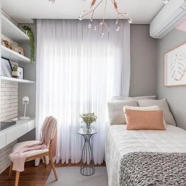 Small bedroom with pink accents white bedding and modern chandelier