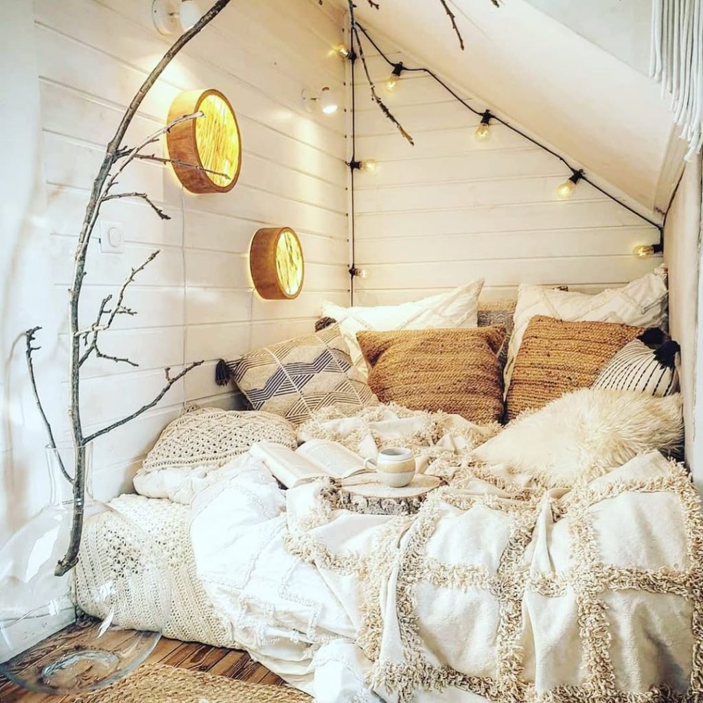 Reading nook with string lights wooden branch decor and textured pillows