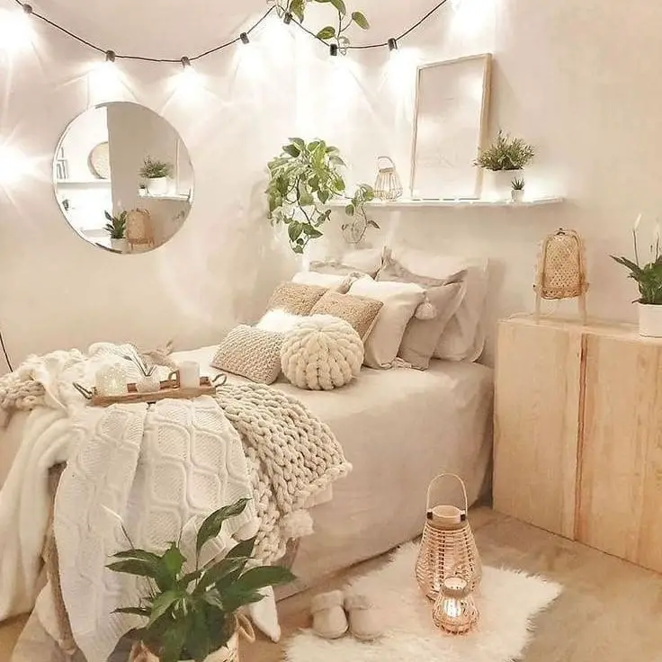 White bedroom with chunky knit throws string lights and botanical accents