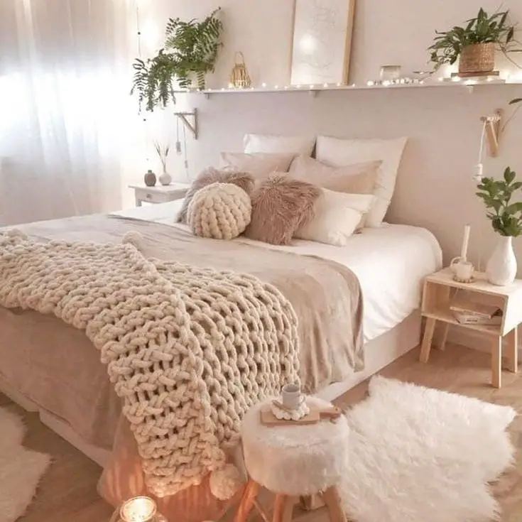 Neutral bedroom with knit blankets fairy lights and floating shelf