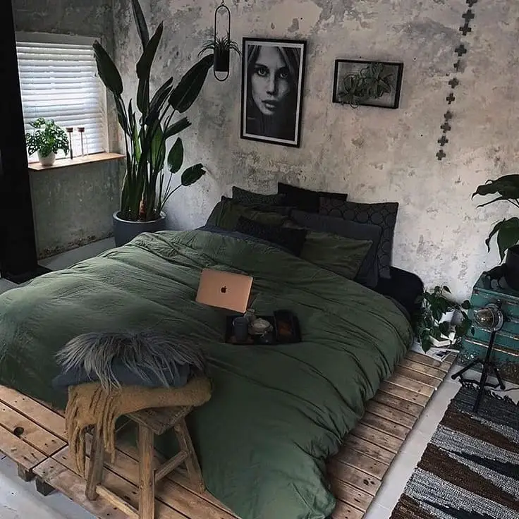 Industrial bedroom with green bedding concrete walls and tropical plants