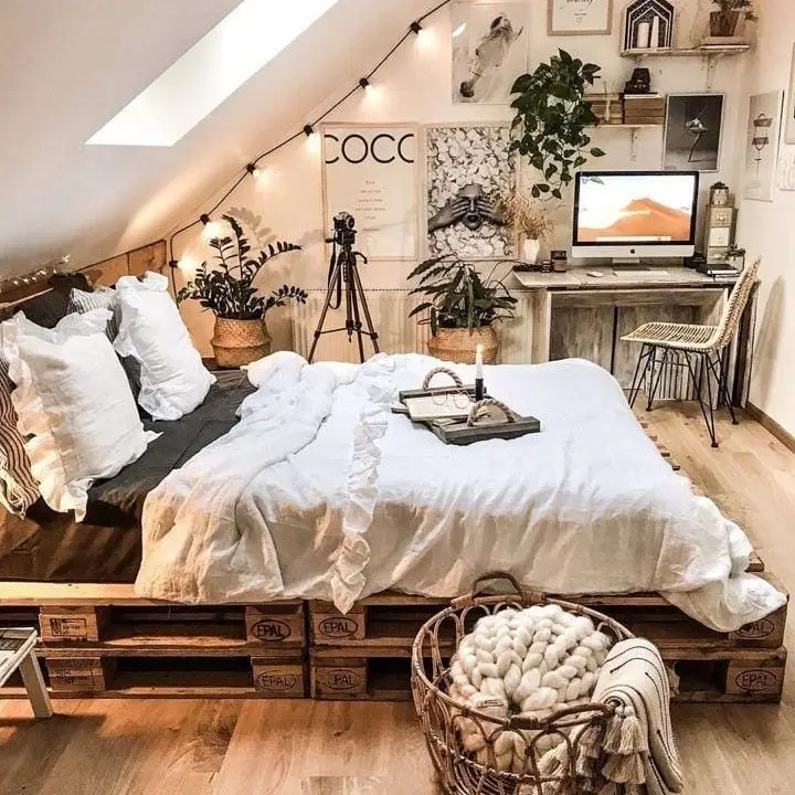 Attic bedroom with pallet bed workspace and string lights
