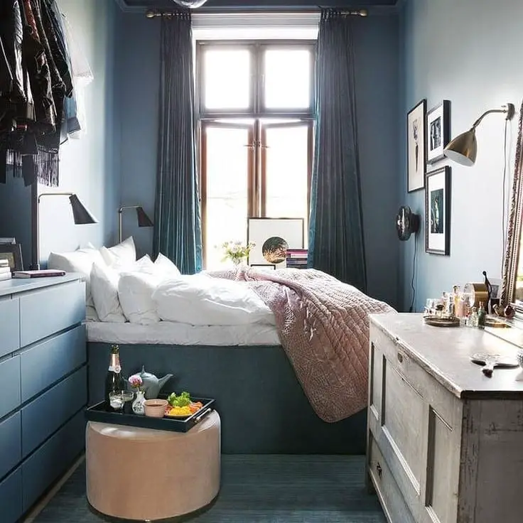 Narrow bedroom with teal walls white bedding and built in storage