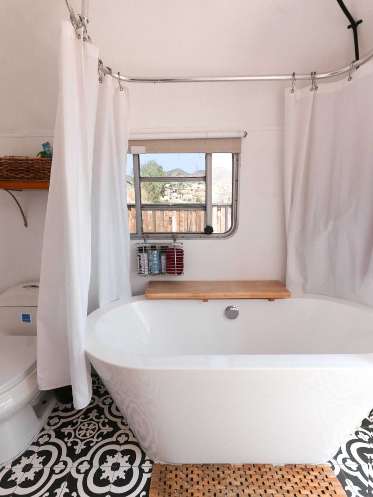Freestanding bathtub with white curtain and patterned floor